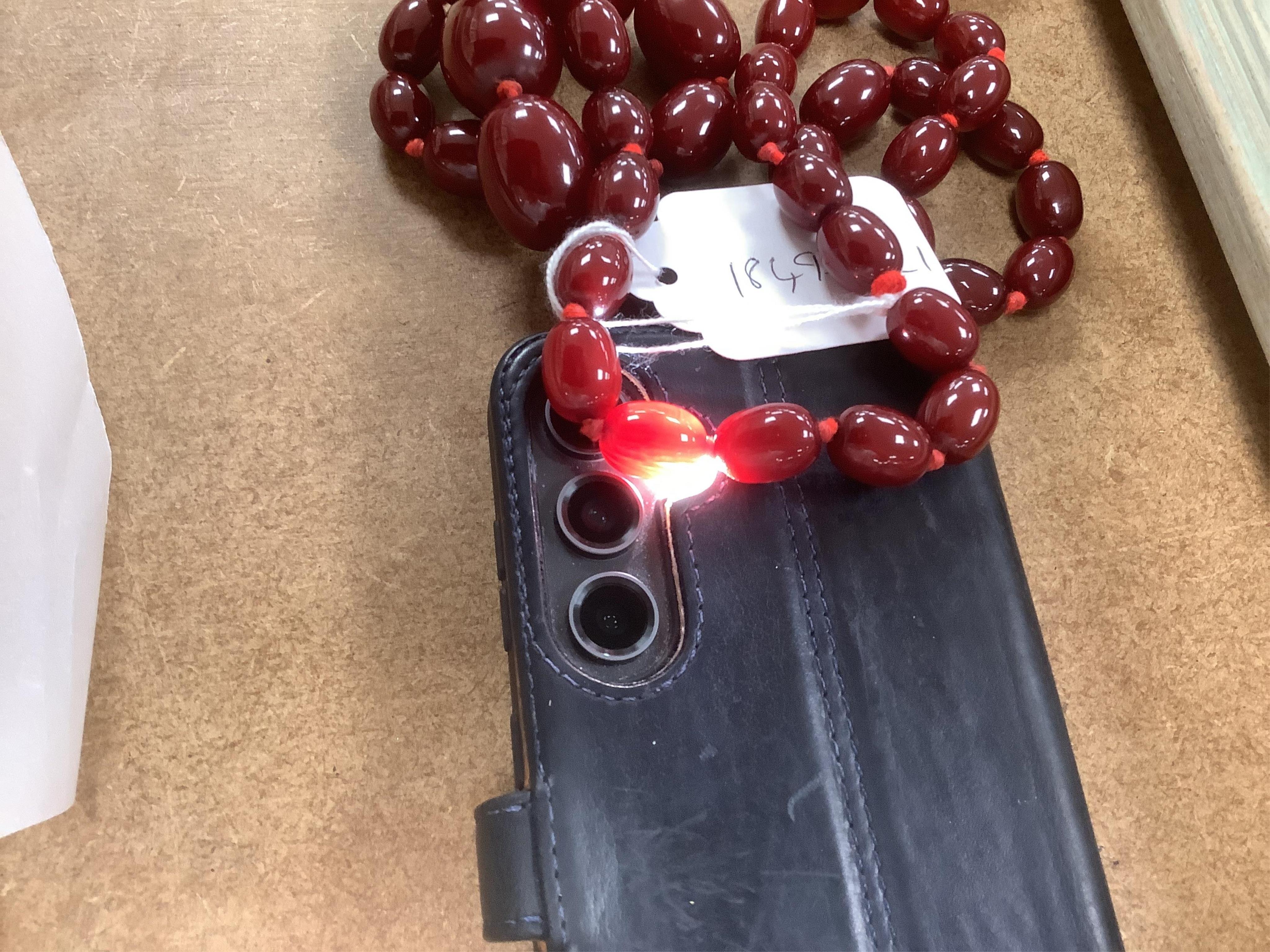 A single strand graduated simulated oval cherry amber bead necklace, 72cm, gross weight 100 grams.